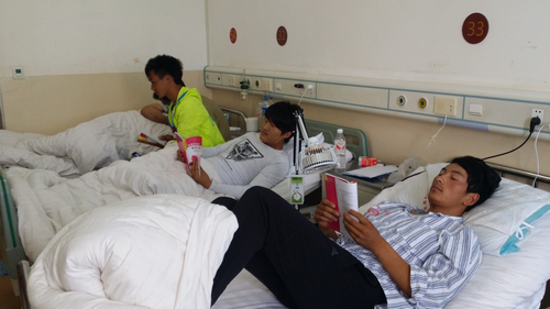 图为受伤人员在病床上阅读《地震伤残康复与护理丛书》