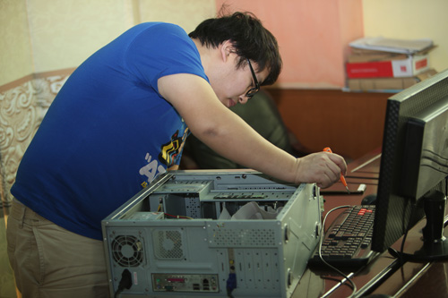 图为中国网络电视台的志愿者为学校检修电脑